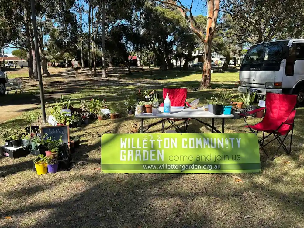 A table surrounded by plants and a green sign at a market